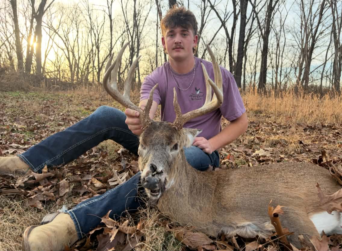 A young hunter with his recovered buck at sunset