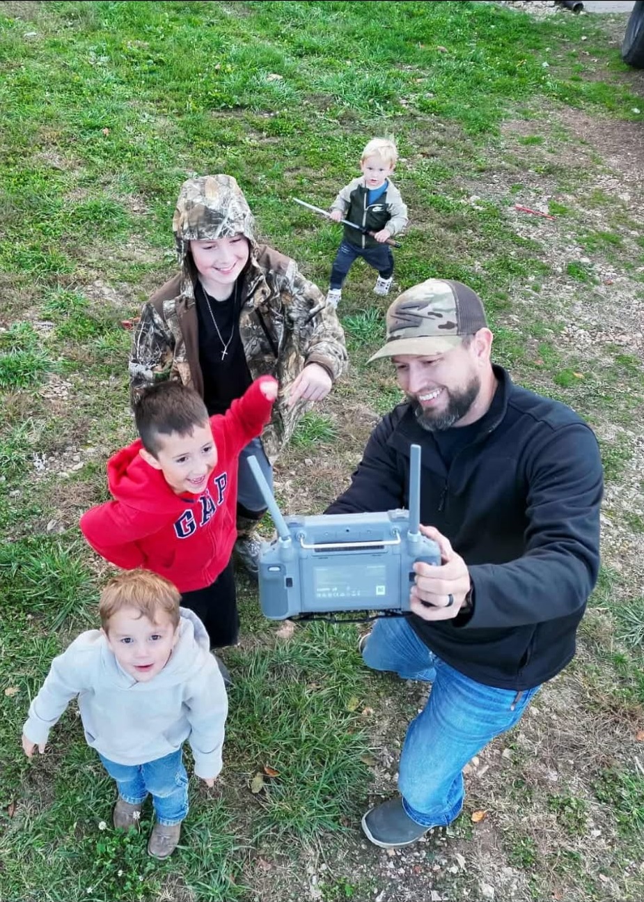 Scotty flying the drone with a group of kids watching